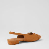 A tan suede slingback flat sandal with a low block heel and a small gold-tone buckle detail on the strap, shown from a side-rear angle against a light gray background.