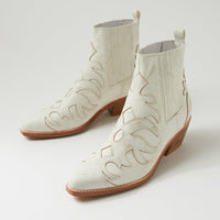 White cowboy boot with brown sole on a light gray background